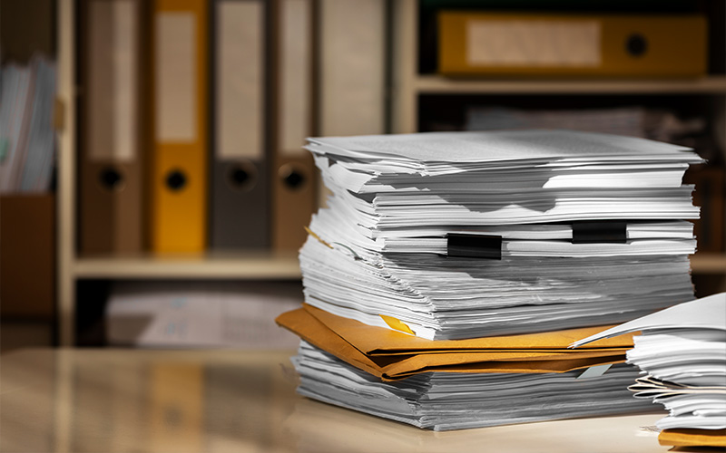 Stack of messy financial paperwork on desk.