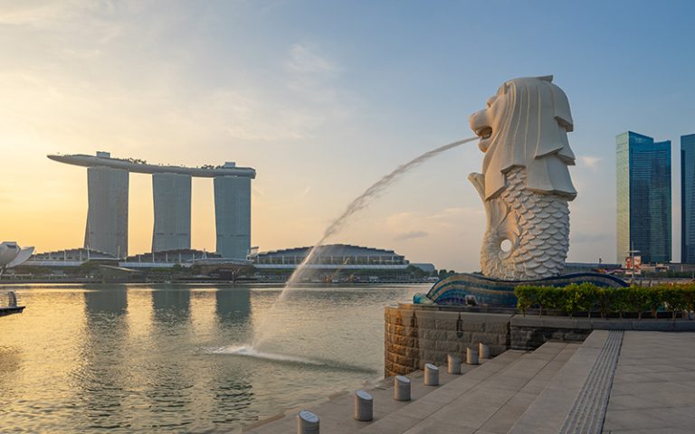 Merlion statue spitting water with Marina Bay Sands background.