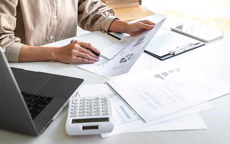 Professional analyzing financial charts and data at a desk.