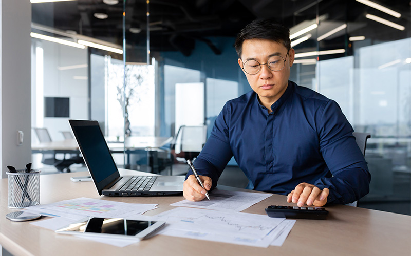 Accountant calculating business expenses on laptop.